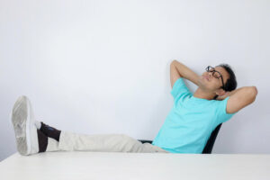 Mężczyzna w pozycji siedzącej wykonuje oddech brzuszny, aby się odstresować.